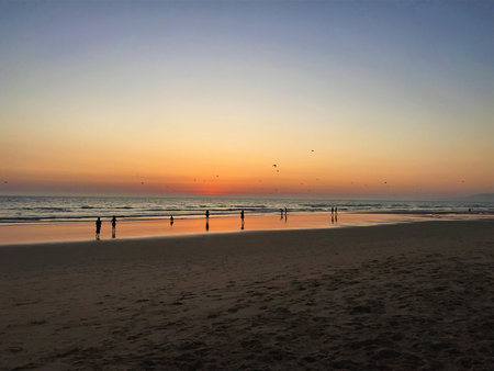 Sunset on the beach with people silhouetted by the wavesの写真素材