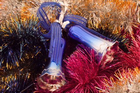 Two Christmas tree bells at the middle of coloured tinselの写真素材