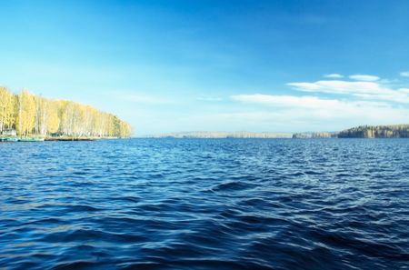 Photo of lake water under blue autumn skyの写真素材