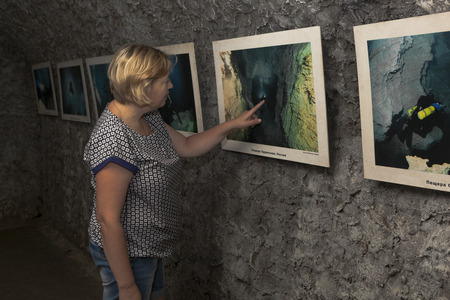 Woman examines a photo exhibition in one of dark halls Caves Bear Safari Park in Gelendzhik, Krasnodar region, Russiaのeditorial素材