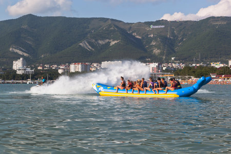 Horseback on an inflatable raft in Gelendzhik Bay. Driver of motorcycle aqueous drenches water attraction participants. Beach resort Gelendzhik, Krasnodar region, Russiaのeditorial素材