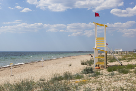 Rescue tower with a red flag on the beach of the resort village Vitino in the Saksky district of the Crimea, Russiaの写真素材