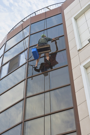 Evpatoria, Crimea, Russia - June 29, 2018: Industrial climber washes windows of an office buildingのeditorial素材