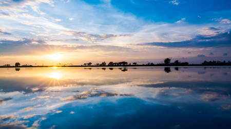 Beautiful reflection of shining sunrise with blue sky and soft cloudの写真素材