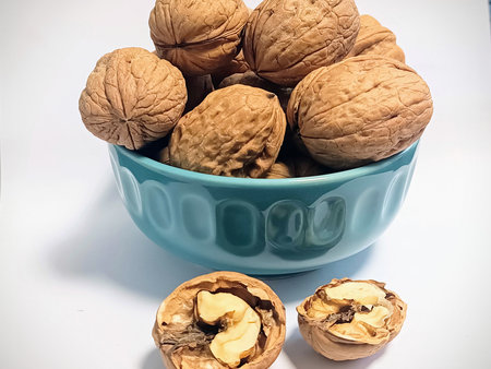 Walnuts in a blue bowl on a white background. Toned.