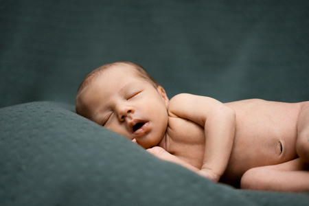 Sleeping newborn baby on green blanket. Beautiful portrait of little child girl 21 days, three week old.の写真素材
