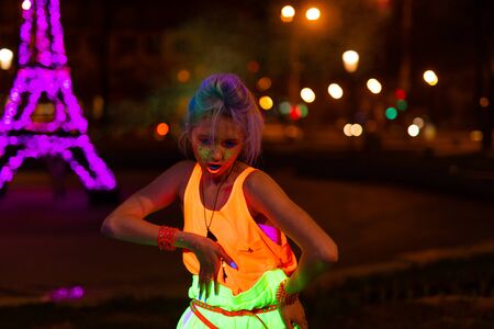 girl in ultraviolet clothes pants and t-shirts posing in the night cityの写真素材