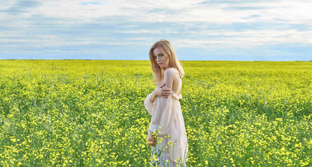 girl in a yellow dress sits in a field with yellow flowers