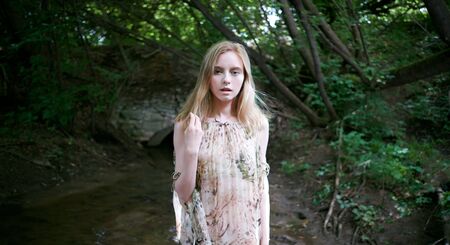 girl by the river on a background of green forestの写真素材