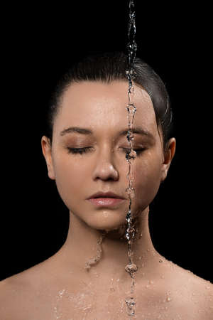 young woman with clean skin and splash of water. Portrait of woman with drops of water around her face black and whiteの写真素材