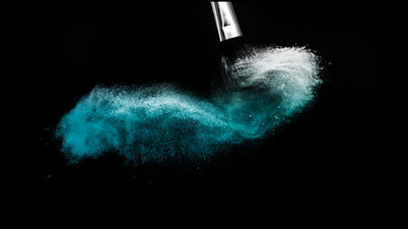 Cosmetic brush with blue cosmetic powder spreading for makeup artist and graphic design in black backgroundの写真素材