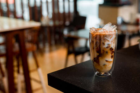 Close-up glass of iced coffee with milk on the tableの写真素材