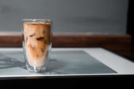 Close-up glass of iced coffee with milk on the tableの写真素材