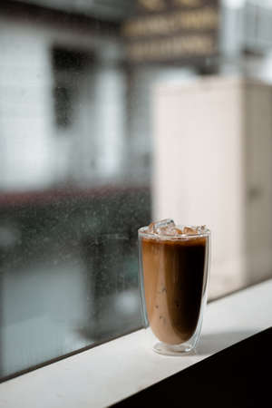 Close-up glass of iced coffee with milk on the tableの写真素材