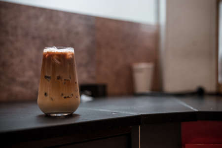 Close-up glass of iced coffee with milk on the tableの写真素材