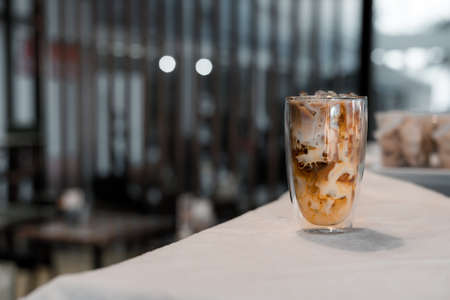 Close-up glass of iced coffee with milk on the tableの写真素材