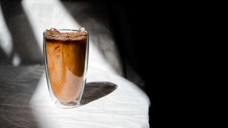 Close-up glass of iced coffee with milk on the tableの写真素材