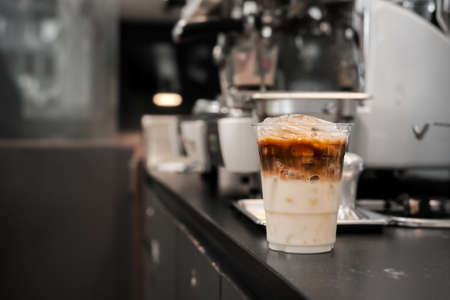 Close-up glass of iced coffee with milk on the tableの写真素材