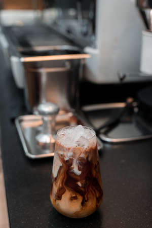 Close-up glass of iced coffee with milk on the tableの写真素材