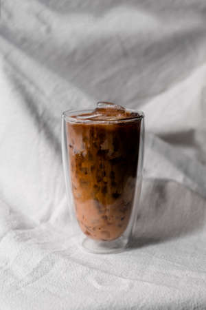 Close-up glass of iced coffee with milk on the tableの写真素材