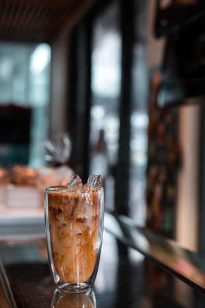 Close-up glass of iced coffee with milk on the tableの写真素材