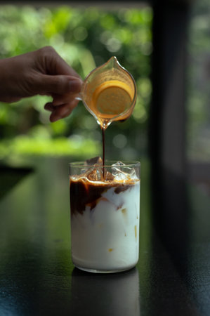 Iced coffee with milk in a glass on a black background.の写真素材