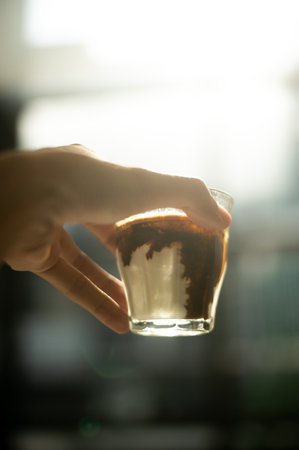 Closeup of a hand holding a glass of hot latte coffeeの写真素材