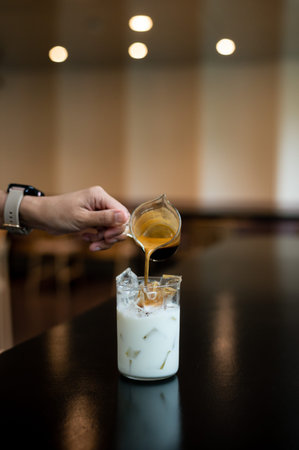 Pouring milk in a glass with ice cream, selective focus.