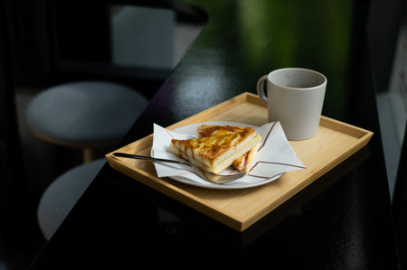 A piece of casserole on a plate with a cup of coffeeの写真素材