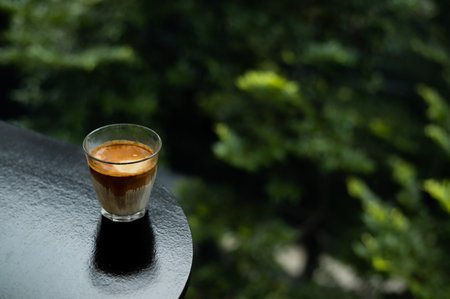 Espresso coffee in a glass on a wooden table with green background