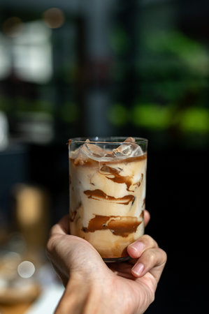 Iced coffee with milk in a glass on a black background.