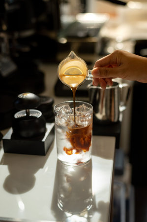 Barista pouring coffee in a glass cup, close-up.