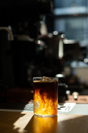 Glass of cola with ice cubes on a wooden table in cafeの写真素材