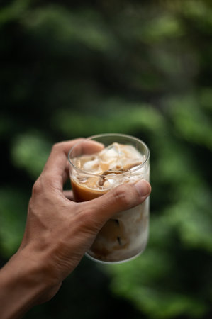 Iced coffee with milk in glass on nature background, soft focusの写真素材