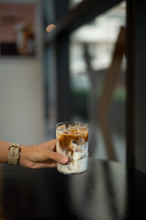 Woman hand holding iced latte coffee in cafe, stock photoの写真素材