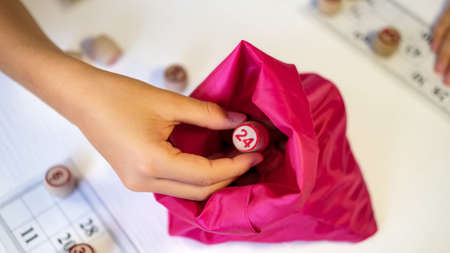 Children play Russian loto on the table. Game of kegs with numbers. take the barrel with the number out of the bag by Handの写真素材