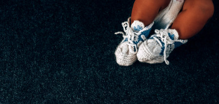 baby feet in knitted blue socks on a black background close-up