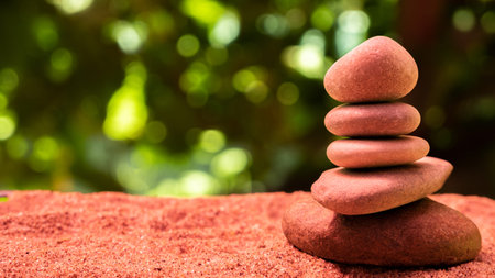 A pyramid of stones on the sand on the beach against a background of leaves