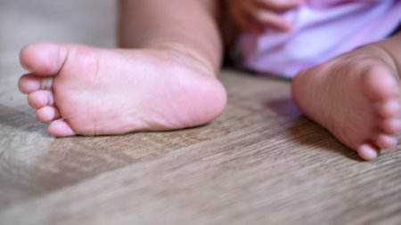 Baby feet on the wood floor. Toes horizontal photo. Close-up.
