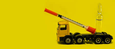 delivery of vaccine against coronavirus, covid19, concept of medical rescue of the world from the virus to humans, yellow lorry delivers vaccine on a yellow background, medicine. Human health. Bannerの写真素材