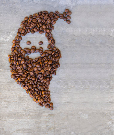 The face of Santa Claus made from coffee beans on a gray textured background. Morning drink....