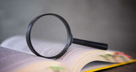 magnifying glass and an open book on a table.の写真素材
