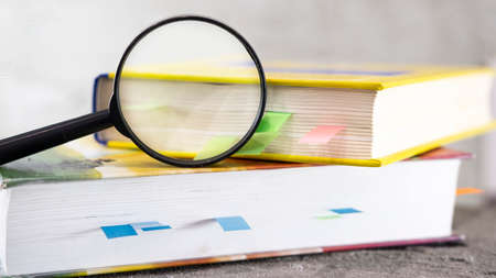 magnifying glass and an open book on a table.の写真素材