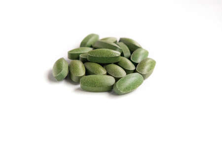 green spirulina pills close up on white background Eco cosmetics concept.の写真素材