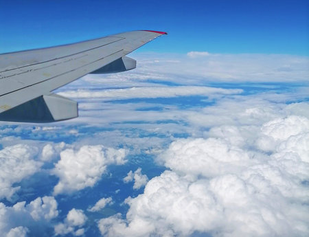 Viewed from airplane windows with a wing, blue sky and white cloud.の写真素材