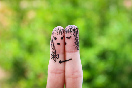 Face painted on the fingers. woman is kissing his girlfriend on the cheekの写真素材