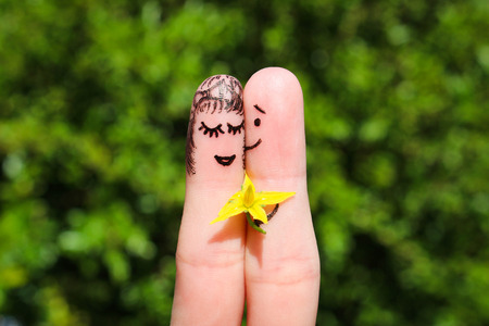 Face painted on fingers. Happy couple. Man is giving flowers to a woman.の写真素材
