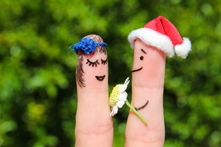 Face painted on fingers. Happy couple. Man is giving flowers to a woman.の写真素材
