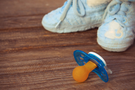 baby shoes and a pacifier on the old wooden backgroundの写真素材