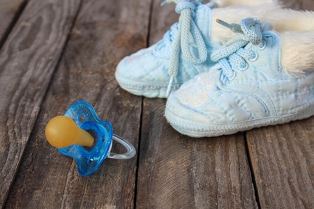 baby shoes and a pacifier on the old wooden background.の写真素材